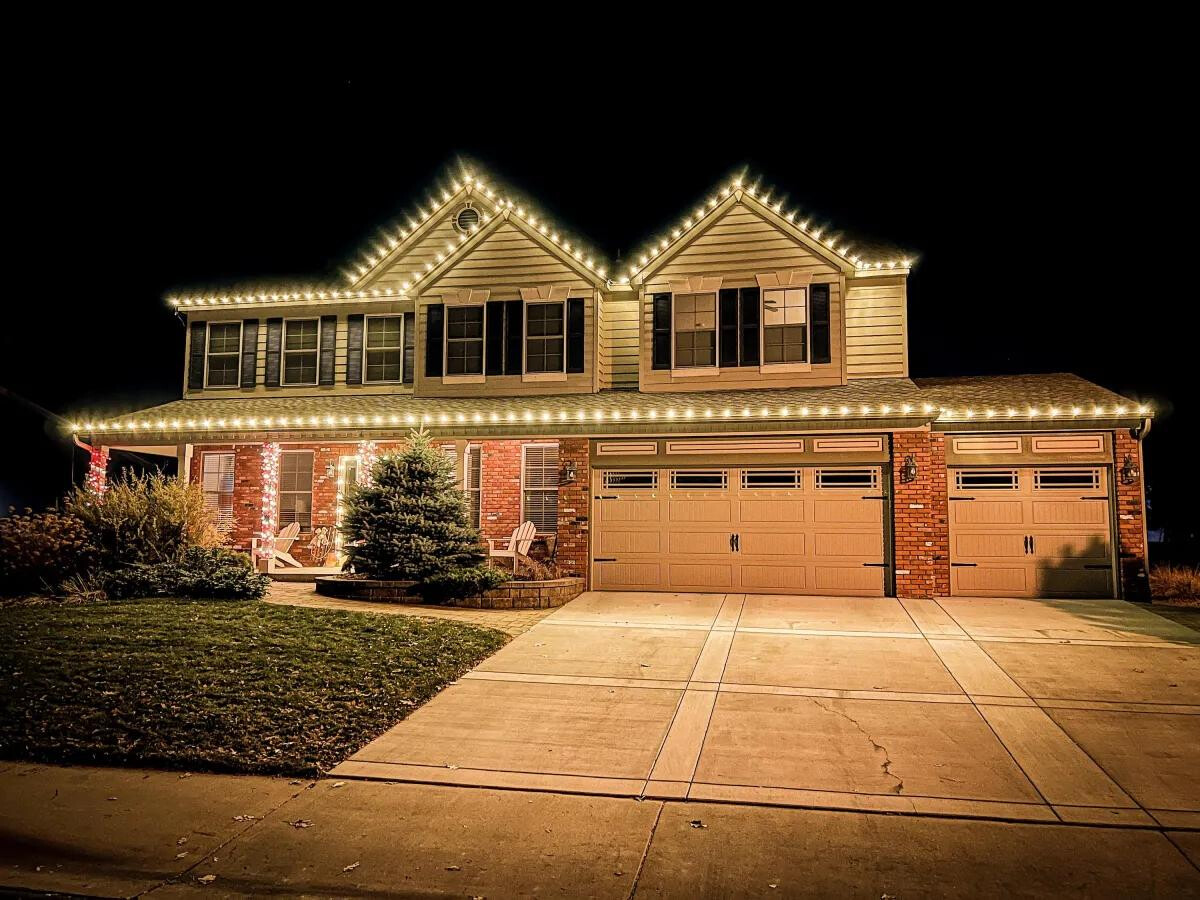 Brick and siding home with warm white gable and roofline Christmas lights