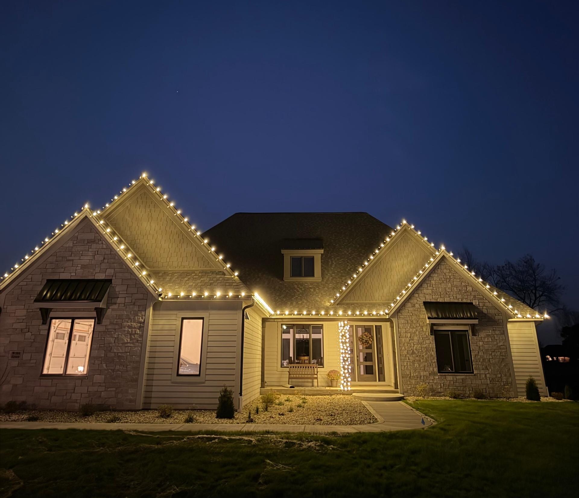 Craftsman home with warm white gable and roofline Christmas lights at dusk