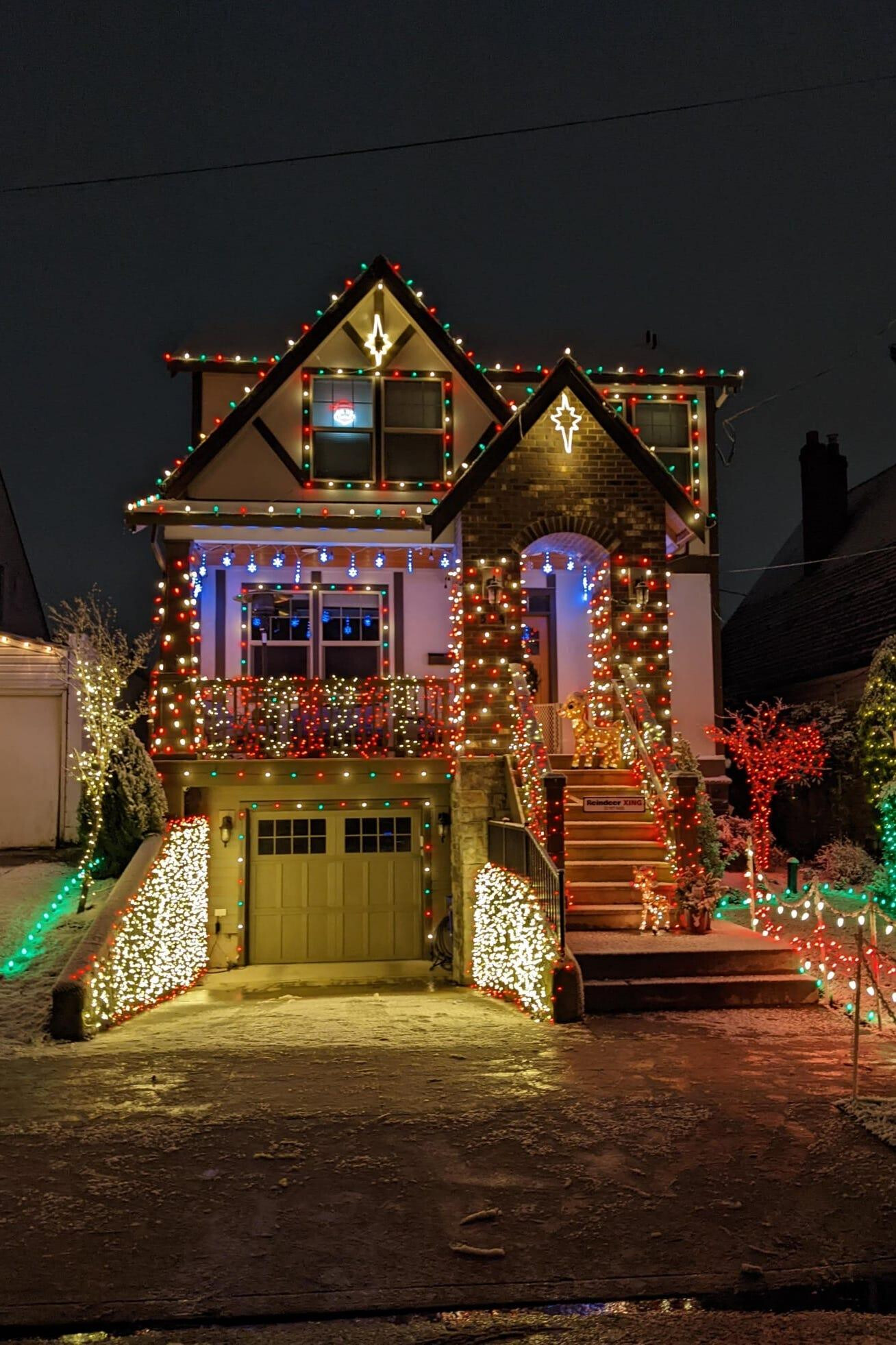 Craftsman home with multicolor Christmas lights, gable stars, and wrapped trees