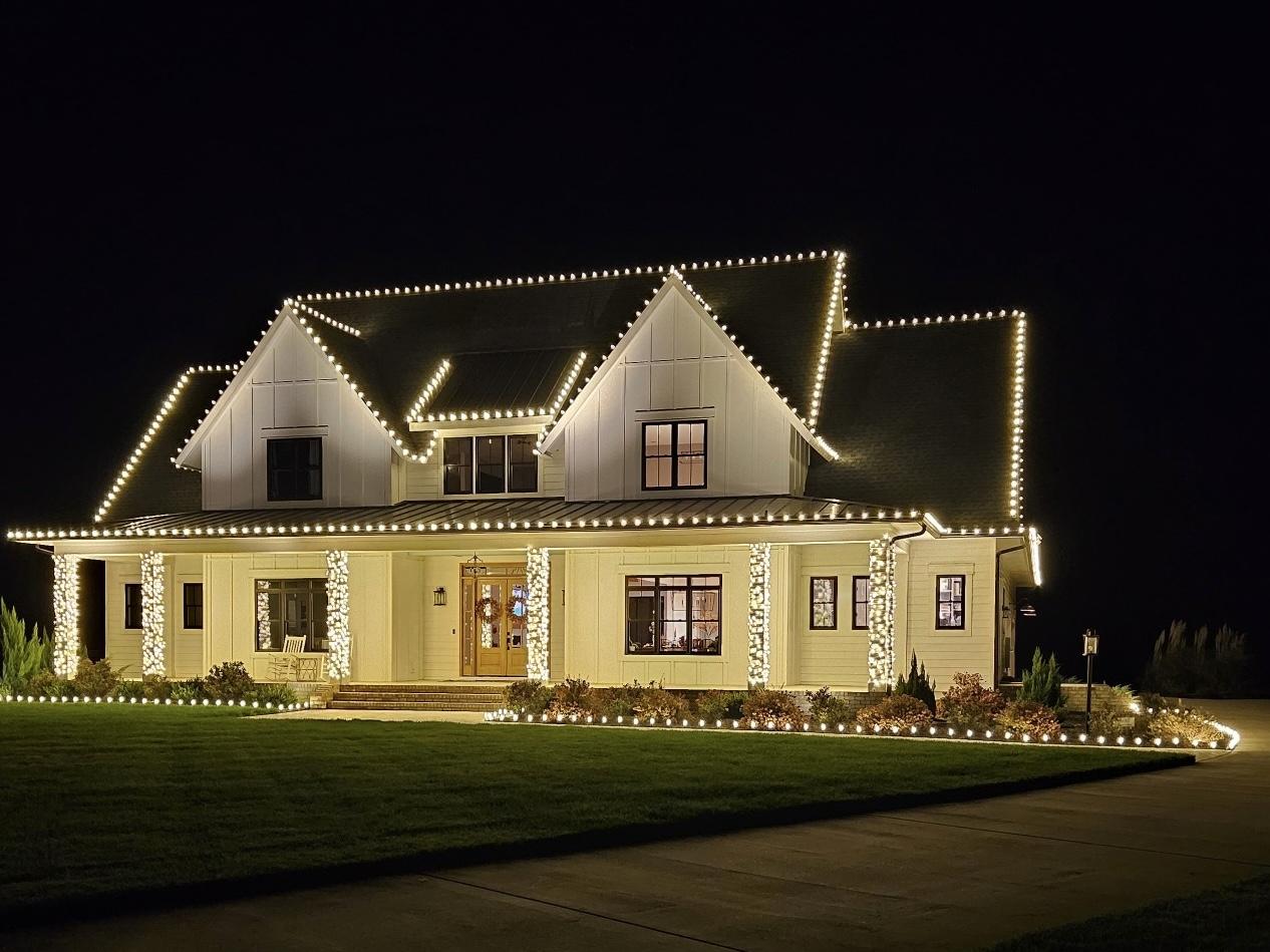 Modern farmhouse with warm white roofline and column Christmas lights
